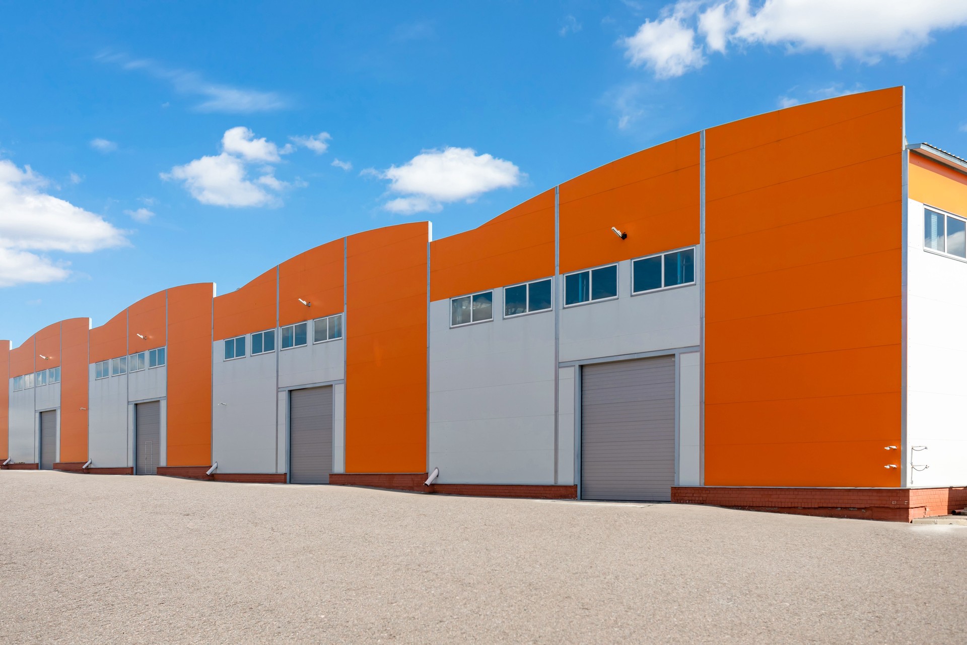 Orange facades with rising gates. Warehouses, logistics center or other commercial real estate